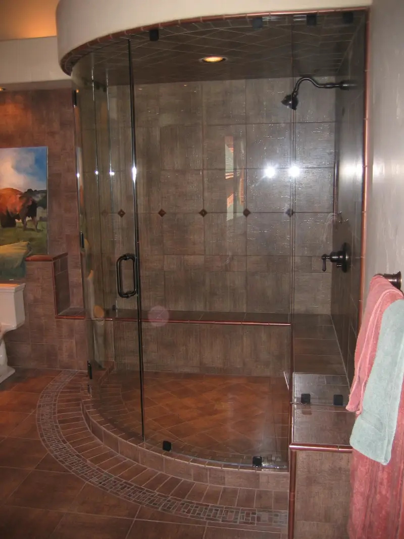 A large glass shower with a bench in the middle.