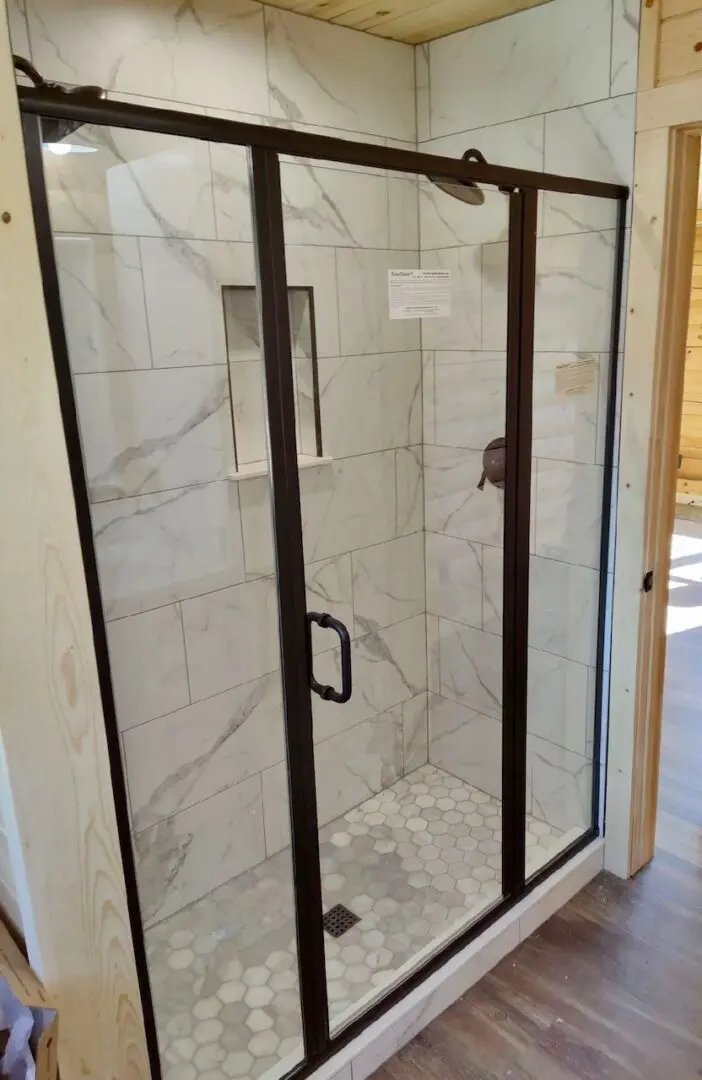 A shower with marble walls and glass doors.